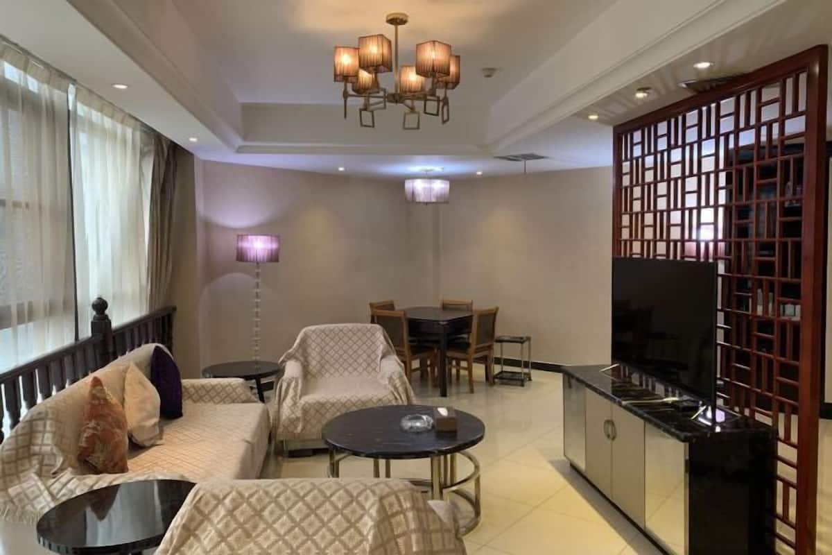 Een moderne woonkamer met een bank, fauteuils, een salontafel, een eettafel en een televisie.