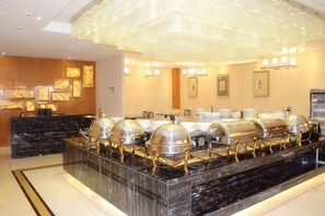 Un buffet avec plusieurs points de service, un comptoir en marbre et un lustre moderne.