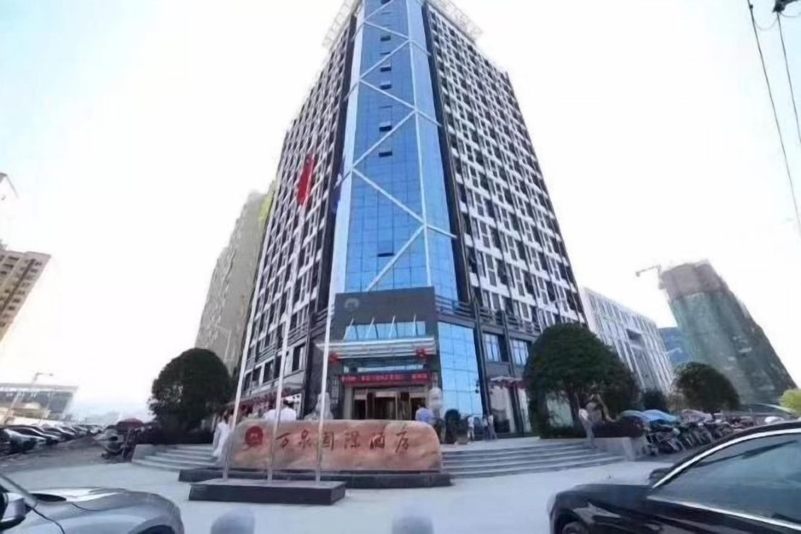 Un edificio de varios pisos con un diseño arquitectónico moderno, que presenta una entrada destacada con fachada de vidrio y un letrero grande.