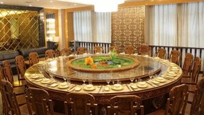 A round dining table with chairs, a decorative centerpiece, and a patterned wall. - Tongcheng Wanquan International Hotel (Tongcheng)
