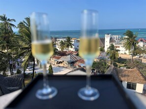 Two glasses of white wine on a tray with a view of a beach and palm trees. - Leparadis Zanzibar Boutique Hotel (Jambiani)