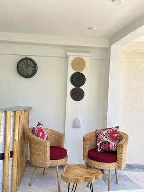 A room with wicker chairs, a wooden table, a wall clock, and decorative woven circles. - Leparadis Zanzibar Boutique Hotel (Jambiani)