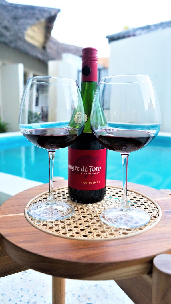 A bottle of wine with two glasses on a table by a pool. - Leparadis Zanzibar Boutique Hotel (Jambiani)