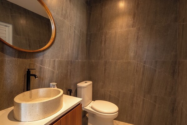 A modern bathroom with a freestanding sink, a toilet, and a wall-mounted mirror. -  Solencia Villa by Betterplace (Jimbaran)
