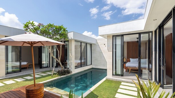 Una casa moderna con piscina, puertas de vidrio y terraza de madera.