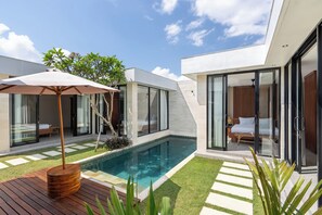 A modern house with a swimming pool, glass doors, and a wooden deck. -  Solencia Villa by Betterplace (Jimbaran)