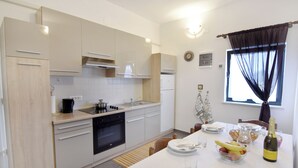 Una cocina moderna con armarios blancos, una estufa negra y un comedor con una mesa lista para dos.