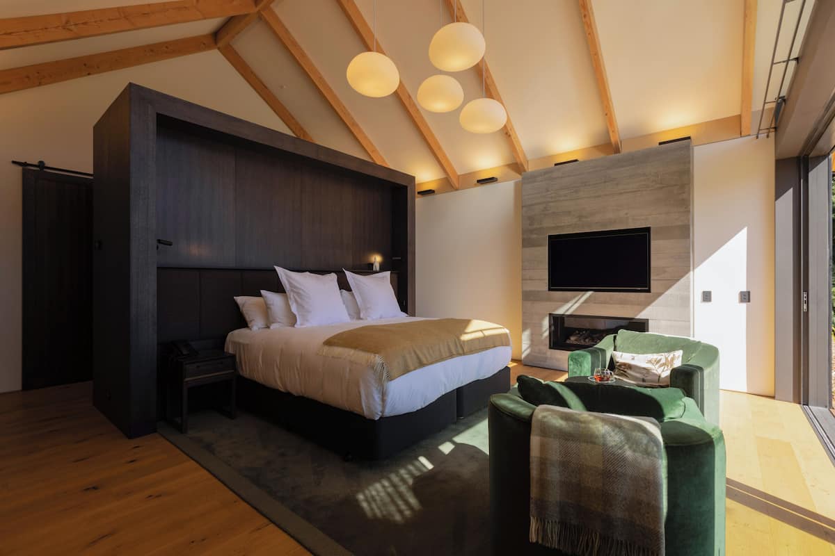 A modern bedroom with a large bed, a TV, and a fireplace.