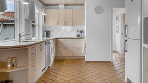 A modern kitchen with white cabinets, a built-in dishwasher, and a tiled floor. - "Kalli" - 100m from the sea by Interhome (Sydals)