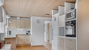 A modern kitchen with white cabinets, a tiled floor, and a wooden ceiling. - "Kalli" - 100m from the sea by Interhome (Sydals)