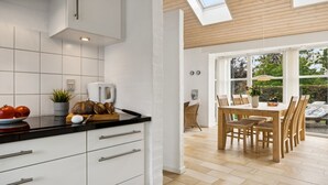 A modern kitchen with white cabinets, a black countertop, and a skylight.