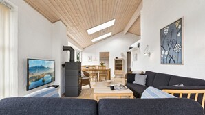 A modern living room with a fireplace, a dining area, and a large window.