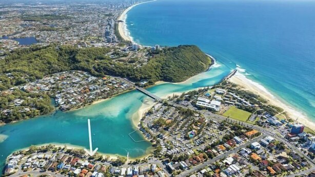 An aerial view of a coastal city with a beach, dense residential area, and a large body of water. - Grevillea on the Beach (Gold Coast)