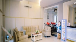 A modern hotel lobby with a reception desk, seating area with sofas, a coffee table, and a decorative wall with a bike sculpture. - Grand Malioboro Yogyakarta Hotel (Gedong Tengen)