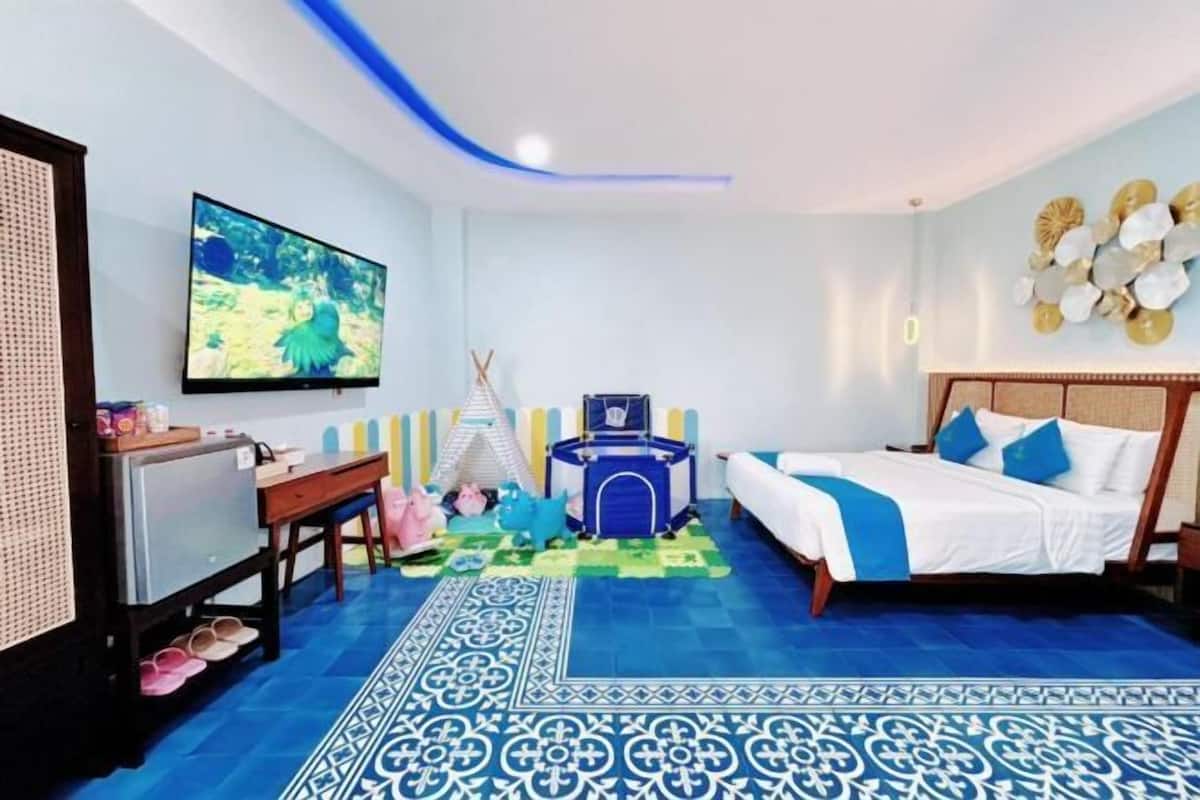 Ein Zimmer mit einem Bett, einem Schreibtisch, einem Fernseher, einer Spielecke mit Spielzeug und einer Wand mit dekorativen Muscheln.