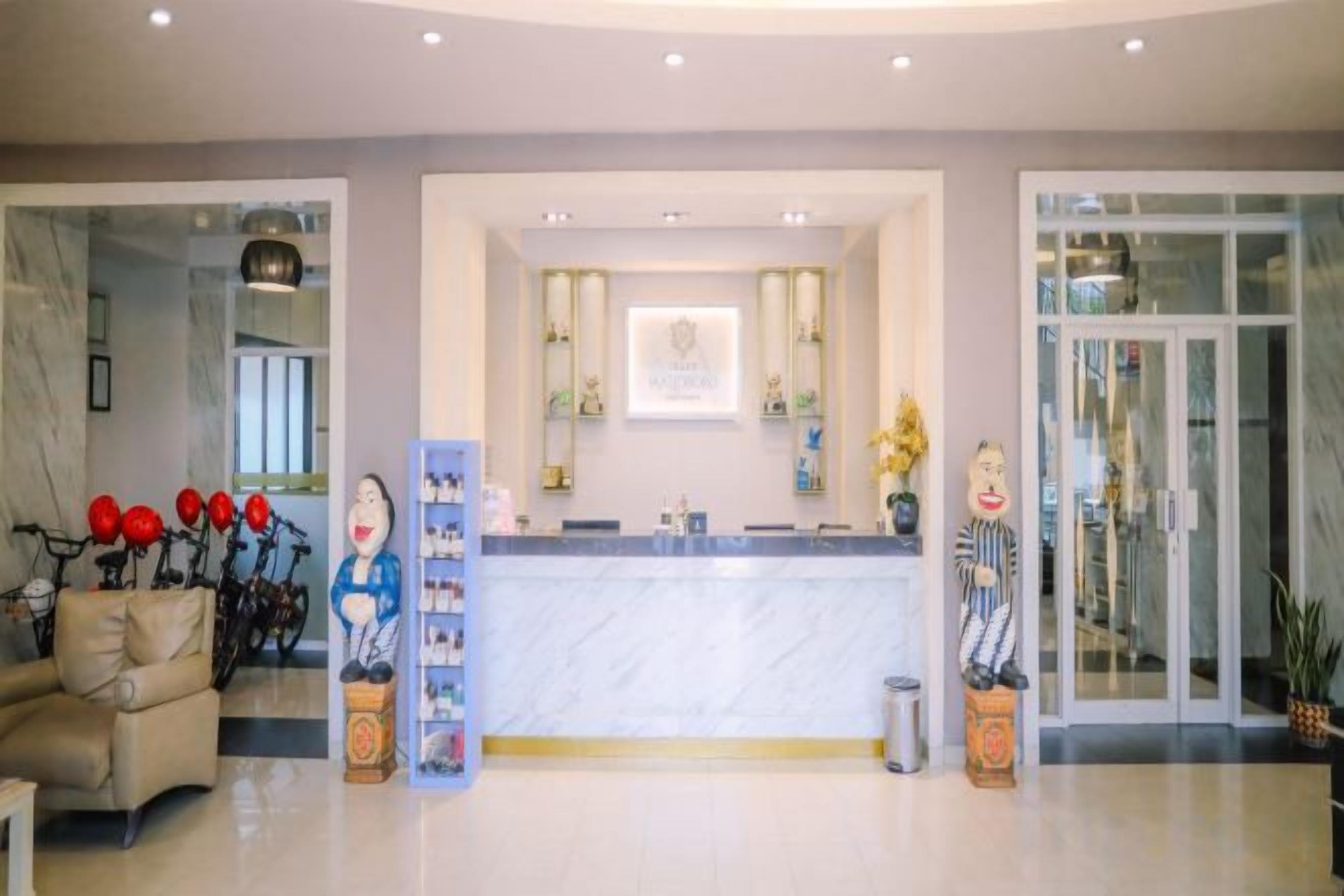 A hotel reception area with a marble counter, a reception desk, and a glass door entrance.