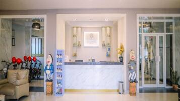 A hotel reception area with a marble counter, a reception desk, and a glass door entrance.