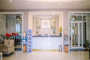 Ein Hotel-Empfangsbereich mit Marmor-Theke, einem Empfangstresen und einem Glastür-Eingang.