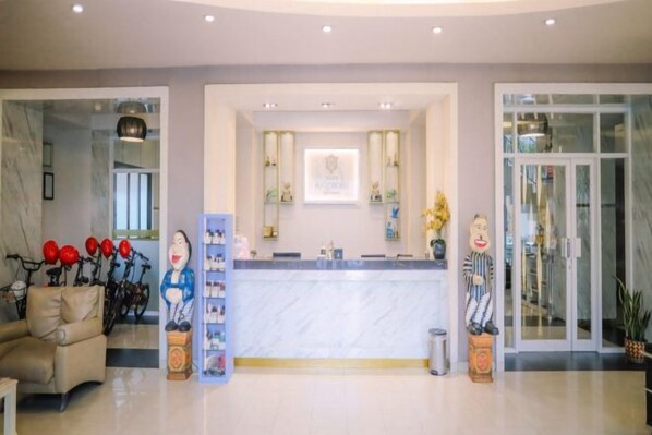 A reception area with a marble counter, a sofa, and a bicycle rack. - Grand Malioboro Yogyakarta Hotel (Gedong Tengen)