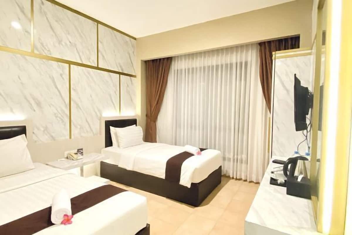 Ein Hotelzimmer mit zwei Betten, einem Fernseher, einem Schreibtisch und einer Marmorwand.