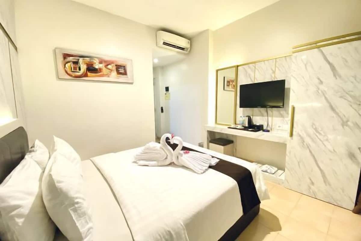 Ein Hotelzimmer mit Bett, Fernseher, Spiegel und einem Gemälde an der Wand.