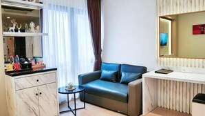 A modern living room with a sofa, a small table, a desk, and a large mirror. - Grand Malioboro Yogyakarta Hotel (Gedong Tengen)