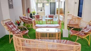 A room with wicker furniture, a round table, and a green carpet.
