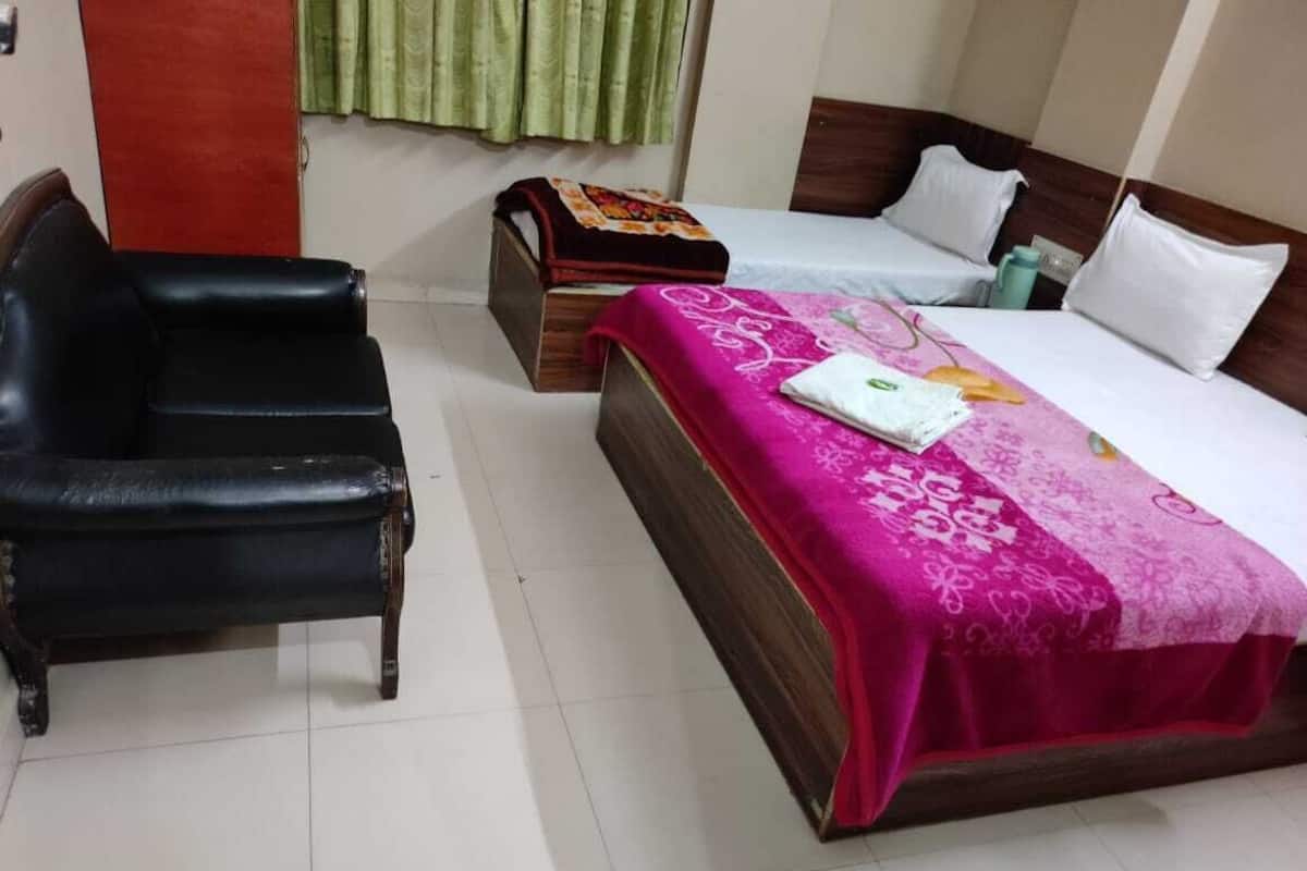 Una habitación de hotel con una cama de madera, una butaca de cuero negro y un pequeño cofre de madera.