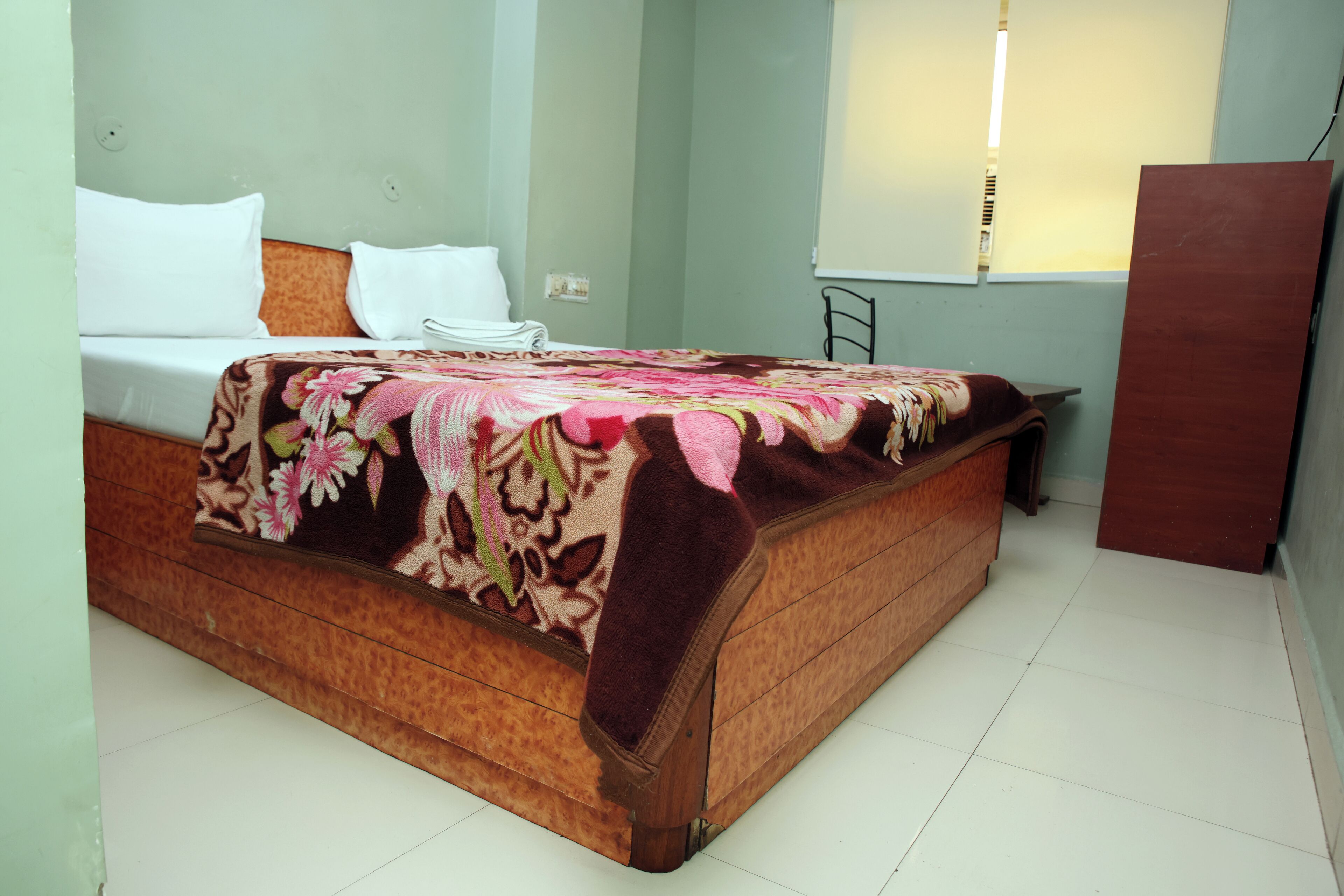 A bed with a floral bedspread, a white pillow, and a wooden headboard.