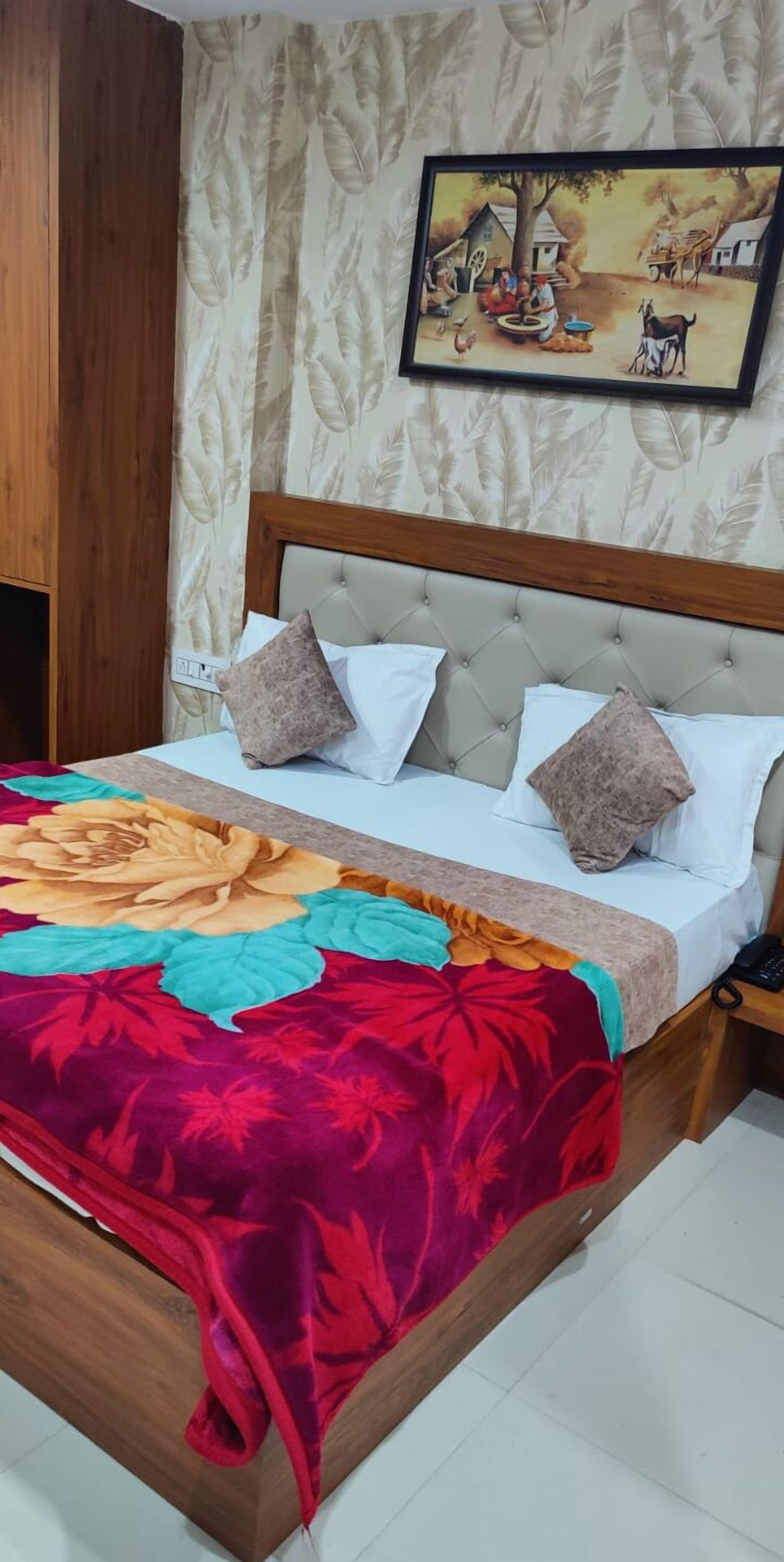 A bedroom with a bed, a headboard, a nightstand, and a painting on the wall.