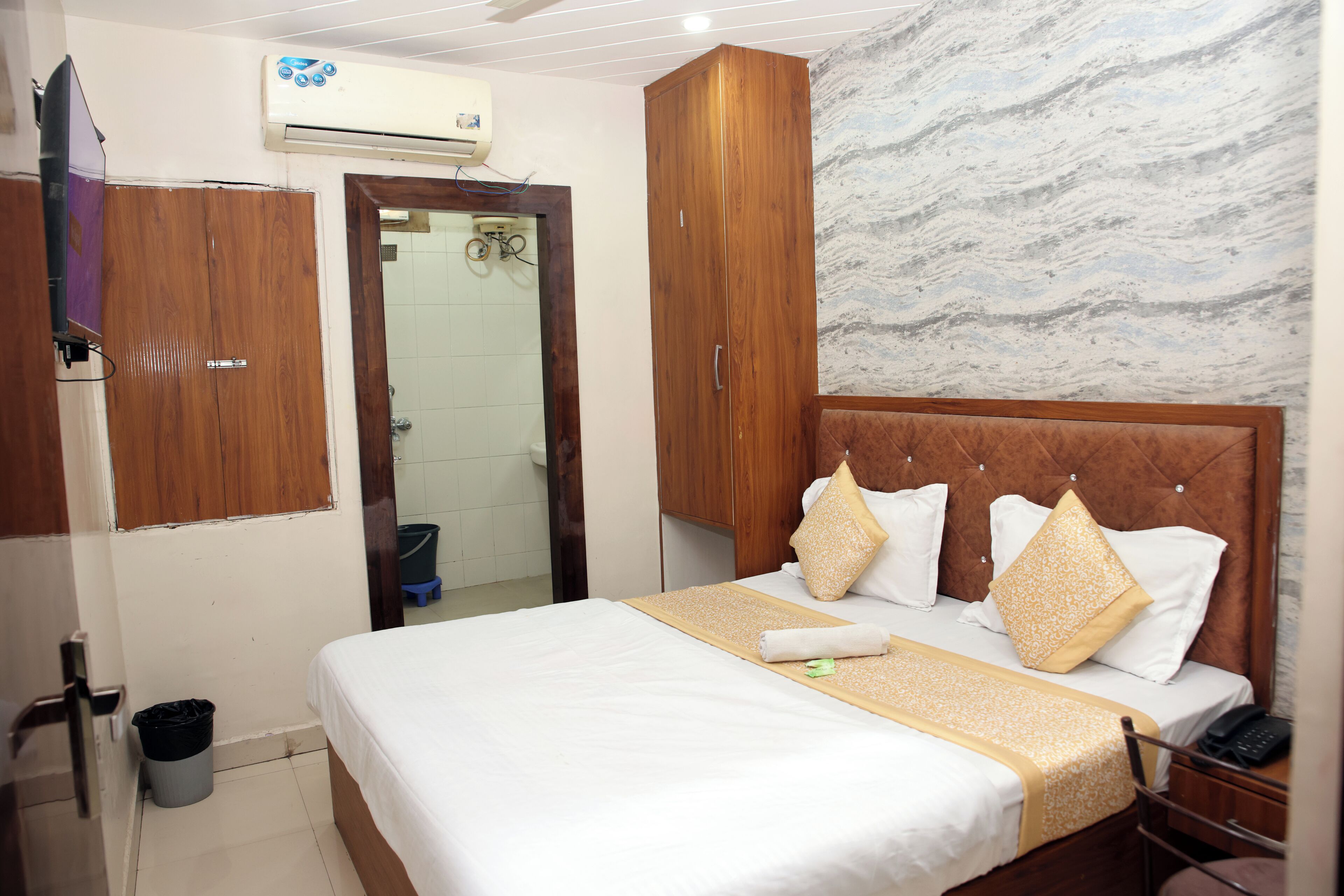 Habitación de hotel con cama, armario de madera y pared de mármol.