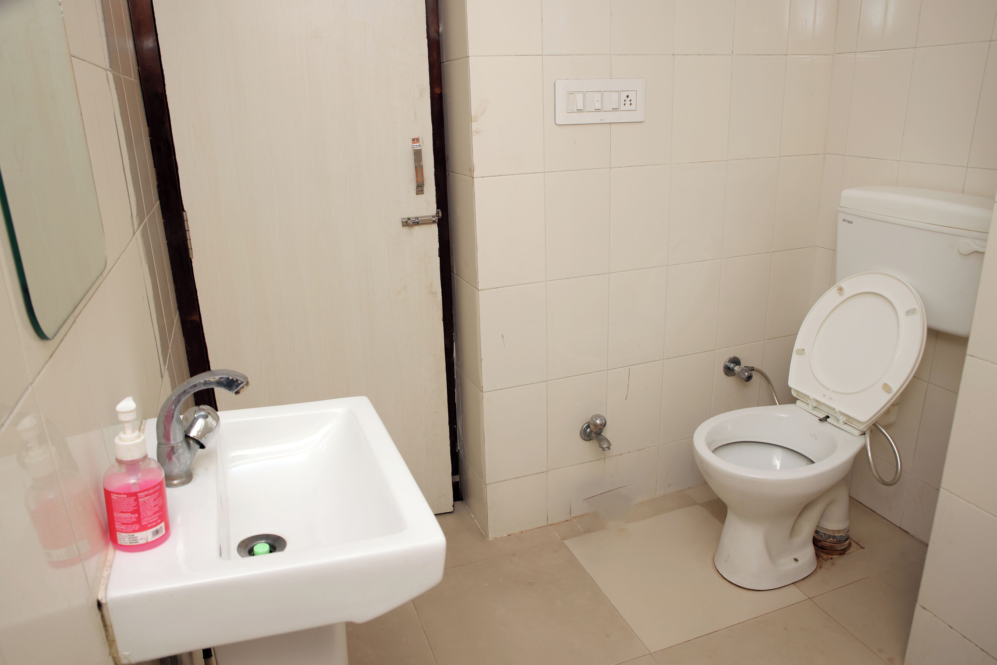 A bathroom with a white sink, a toilet, and a mirror.