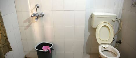 A small bathroom with a toilet, a shower, and a trash bin.