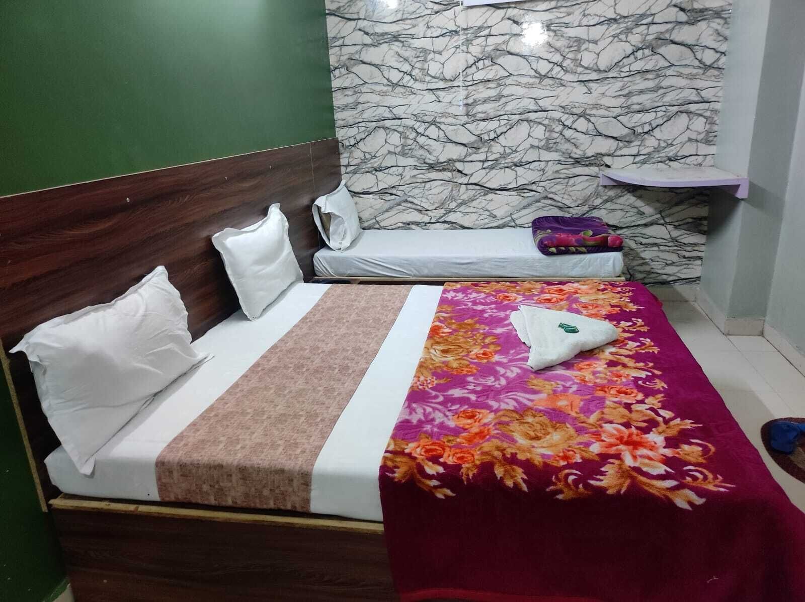 A neatly made bed with white and brown bedding, a floral-patterned blanket, and a pillow.