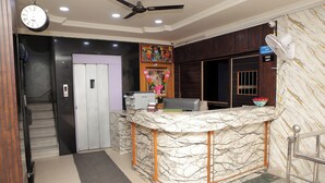 A reception area with a marble counter, a clock, and a ceiling fan.