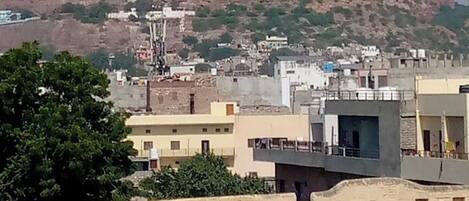 Vista de un paisaje urbano con una colina destacada al fondo, que presenta una estructura similar a una fortaleza.