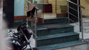 De ingang van Hotel Siddhi Vinayak, met een glazen deur, trappen en een motorfiets voor de deur.