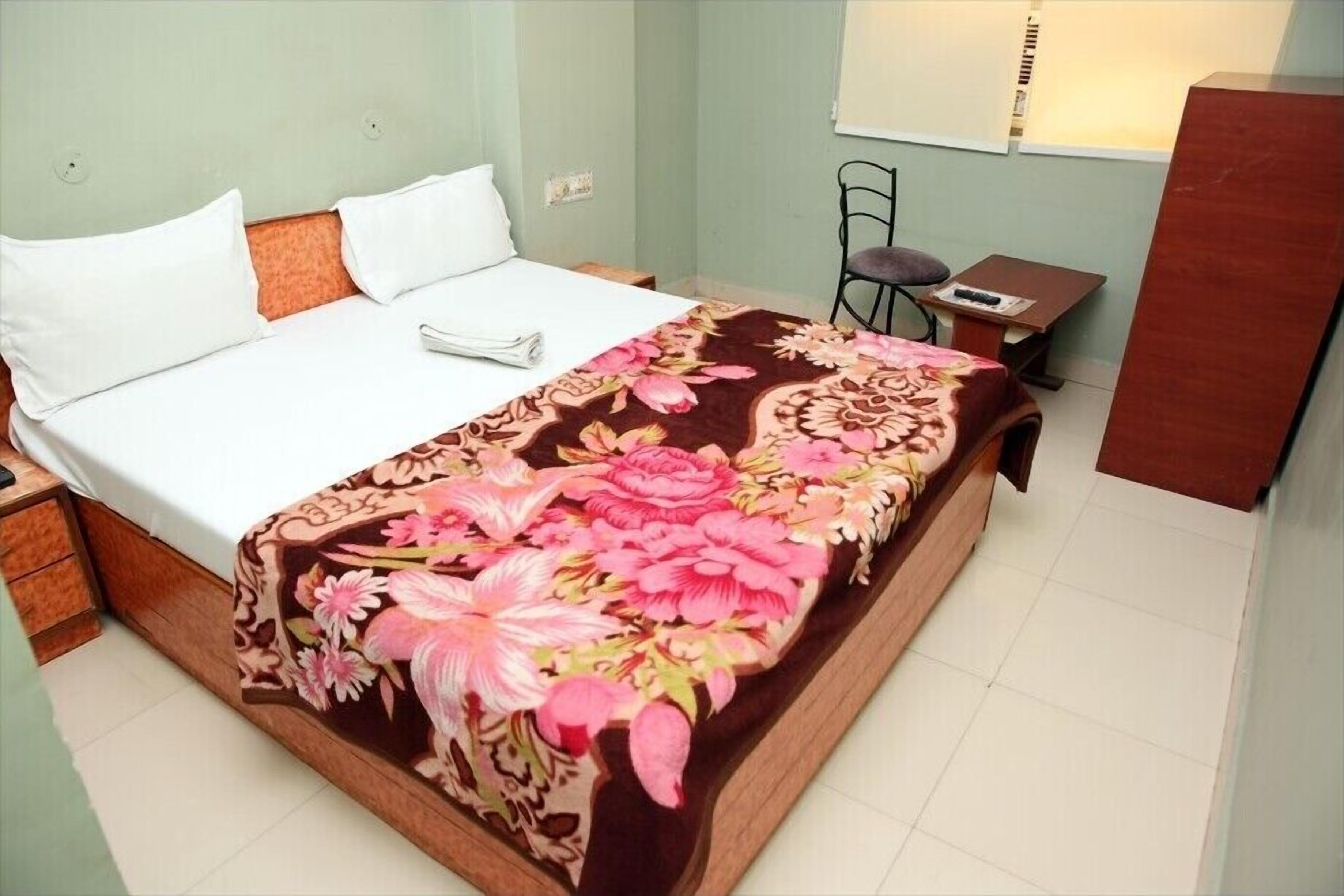 Un dormitorio con cama, mesita de noche, silla y una pequeña mesa.