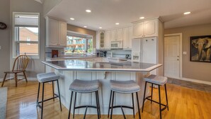 A spacious kitchen with a large island, white cabinetry, and a view to the outside.