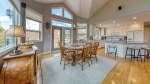 A spacious kitchen with a large island, wooden chairs, and a dining table.