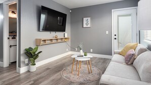 Un salon moderne avec un téléviseur à écran plat, un canapé, une table basse et une plante en pot.