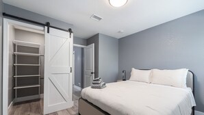 Une chambre à coucher avec un lit, une armoire dont les portes sont ouvertes et une table de chevet.
