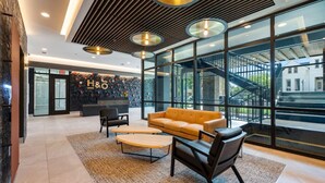 A modern lobby with a reception desk, a sofa, and a coffee table. - Chic Music Row Condo - Pool, Rooftop Deck with City View, Gym, Office + More! (Nashville)