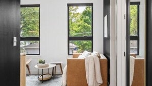 A modern interior with a sofa, a small round table, and a ceiling fan. - Chic Music Row Condo - Pool, Rooftop Deck with City View, Gym, Office + More! (Nashville)