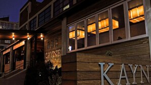 A hotel entrance with a wooden facade and illuminated windows. - Chic Music Row Condo - Pool, Rooftop Deck with City View, Gym, Office + More! (Nashville)
