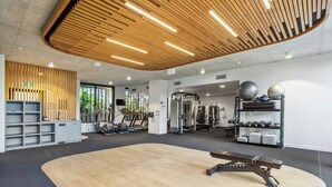 Ein modernes Fitnessstudio mit Holzbalkendecke, Trainingsgeräten und einem großzügigen, offenen Raum.