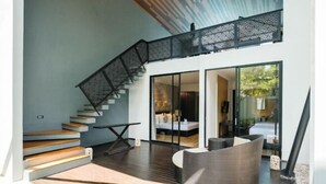 A modern interior with a staircase, a seating area, and a glass door leading to another room. - The Lavana Akatara Villa Nusa Dua (Bali)