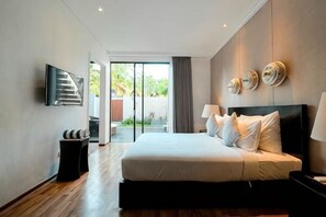 A modern hotel room with a large bed, a flat-screen TV, a small table, and a view of the outdoors. - The Lavana Akatara Villa Nusa Dua (Bali)