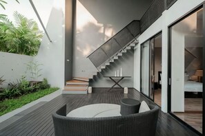 A modern outdoor patio with a staircase leading to a bedroom.