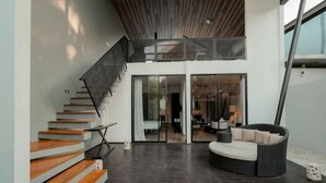 A modern interior with a staircase, a seating area, and a glass door leading to another room. - The Lavana Akatara Villa Nusa Dua (Bali)
